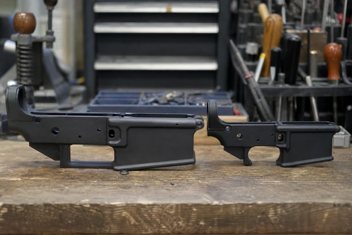 Two AR-style lower receivers sitting on a wooden workbench.