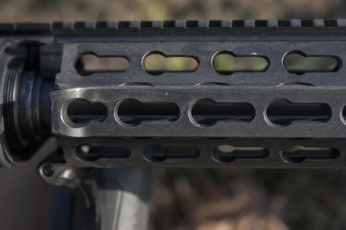 Close-up of a rifle handguard showing the keyhole-shaped slots of the KeyMod mounting system.