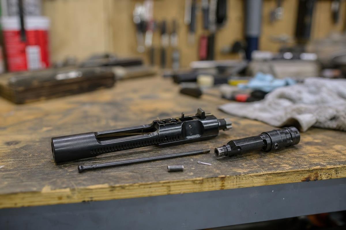 A disassembled bolt carrier group lying on a wooden workbench.