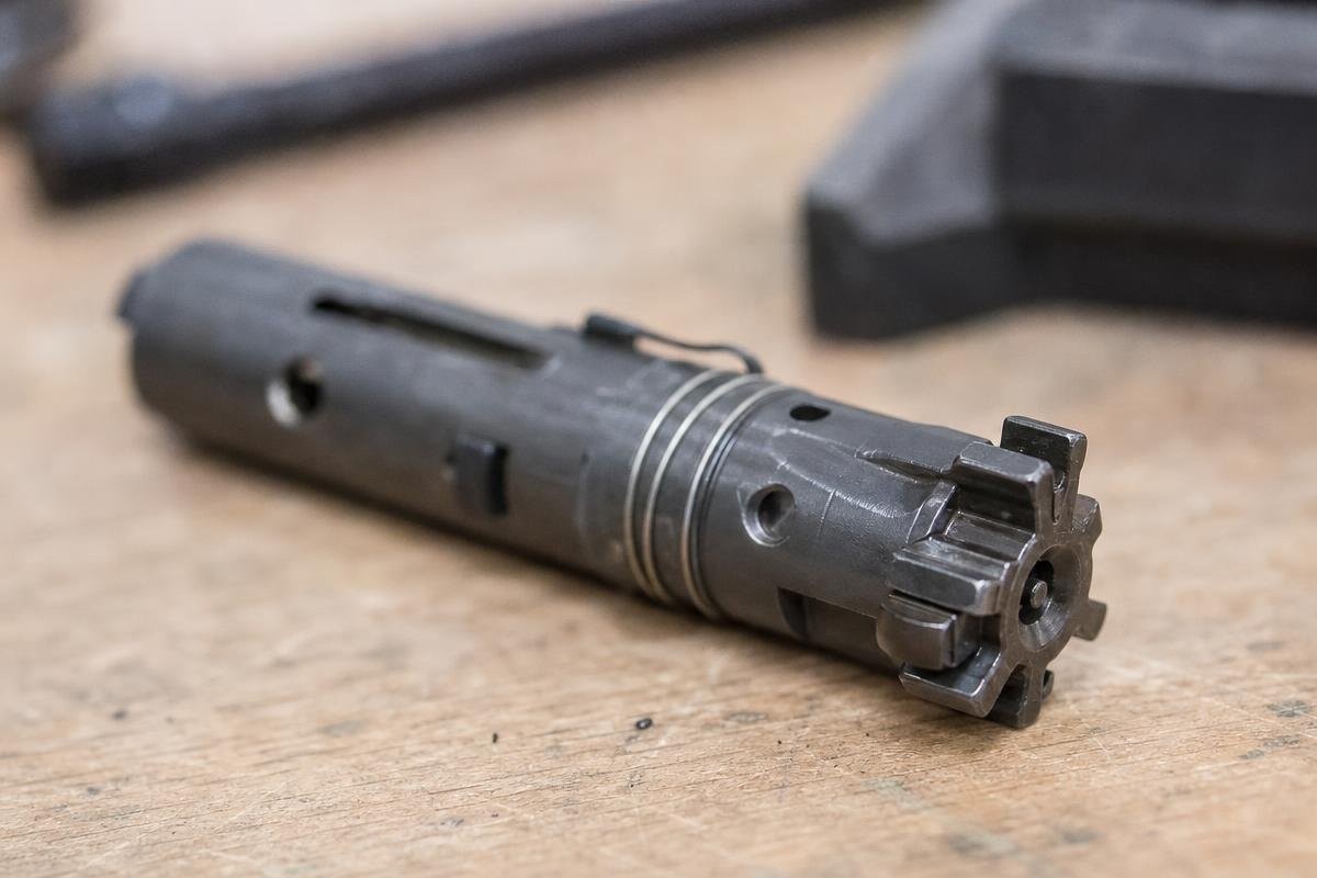 A bolt carrier group resting on a wooden surface after cleaning.