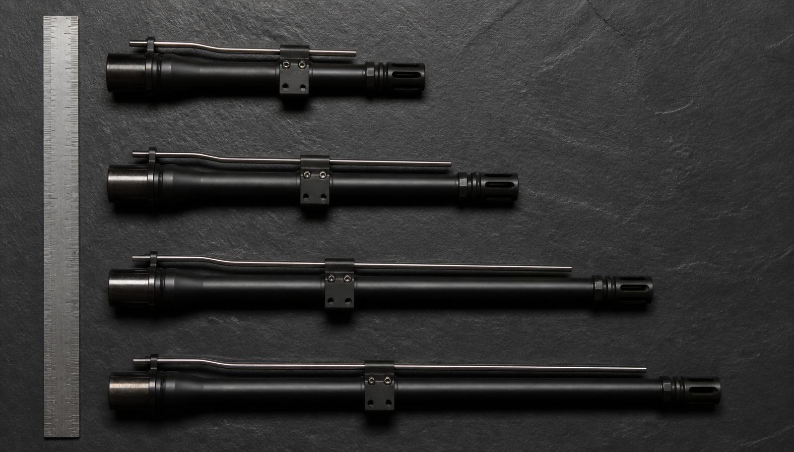 Four AR-15 barrels of different lengths, 7.5 inch, 10.5 inch, 14.5 inch, and 16 inch, arranged in a diagnostic overhead layout with a ruler for scale on dark slate.