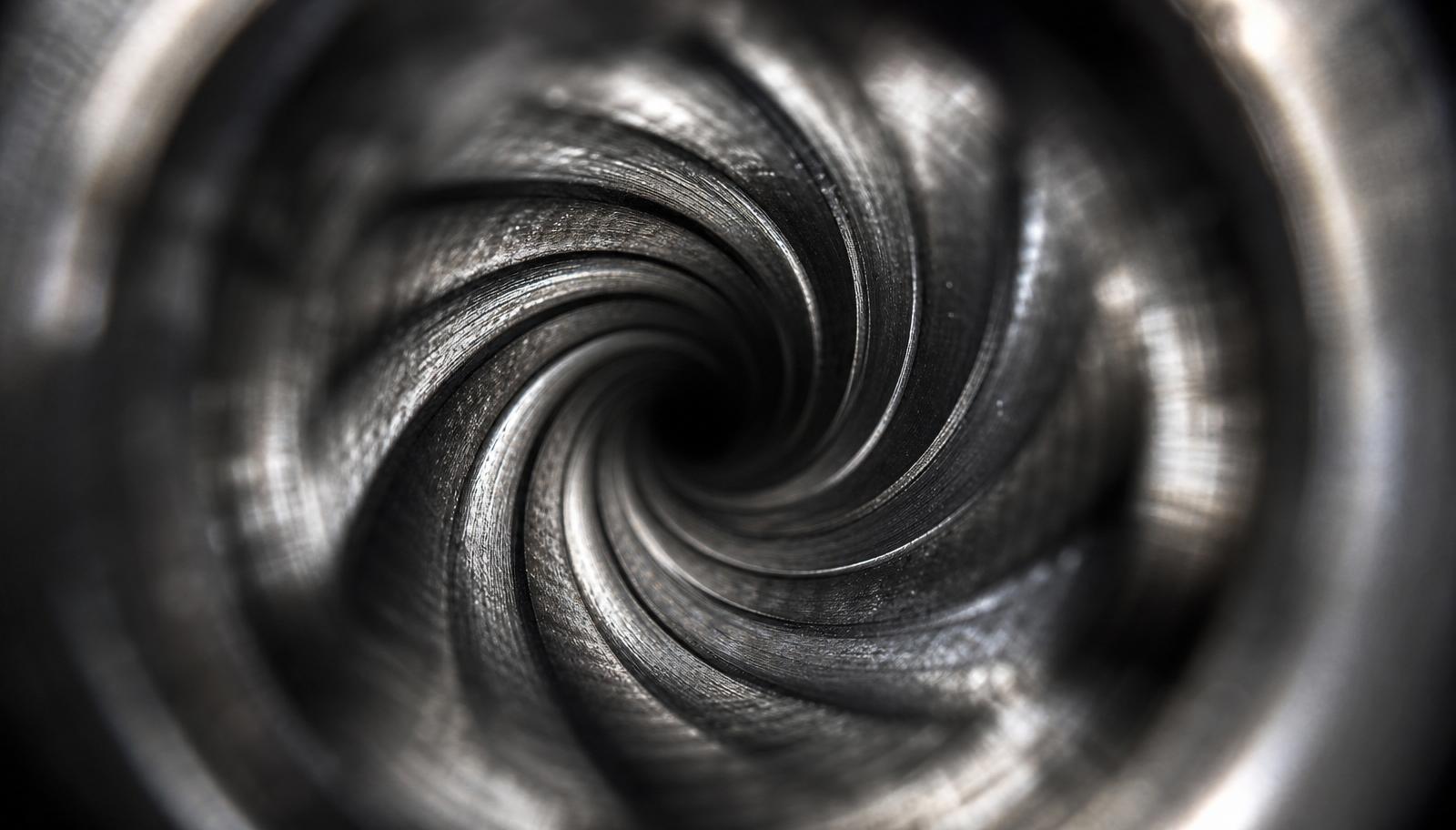 Close up macro view down an AR-15 barrel bore showing the spiral rifling grooves.