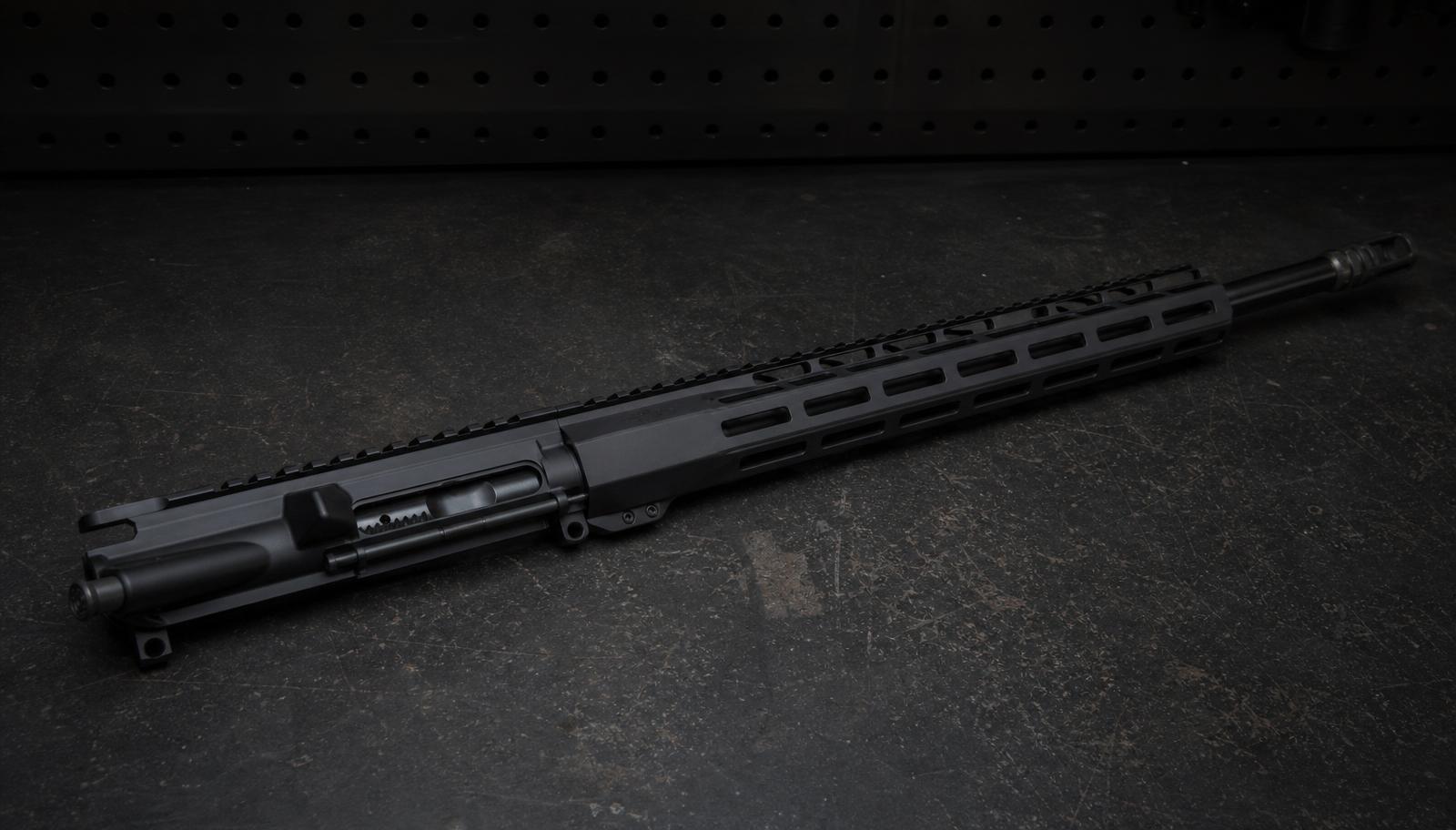A complete AR-15 upper receiver with a 16 inch barrel and standard M-LOK handguard laid on a dark workbench.