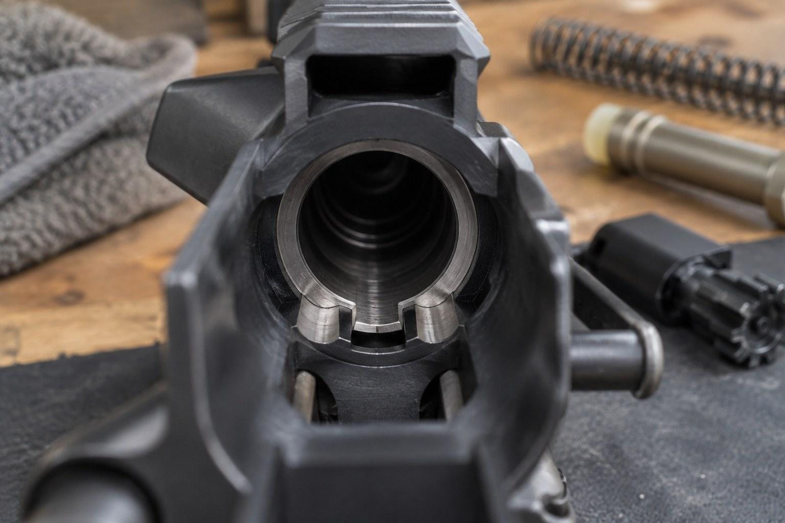 Close view into the circular opening of a black firearm receiver on a workbench
